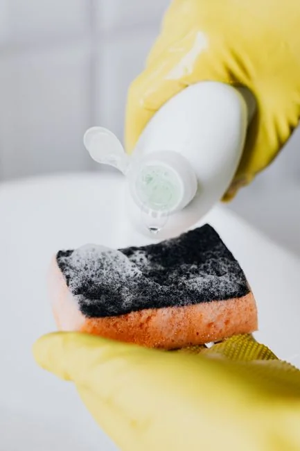 Une femme enveloppe avec soin un canapé dans un matériau de protection tout en emballant des cartons dans une pièce lumineuse.